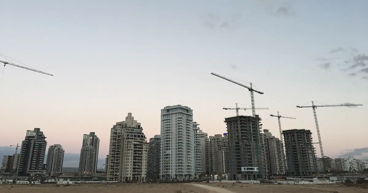מגדלי מגורים חדשים נבנים בשכונת עיר ימים בנתניה, עם עגורנים בשעת דמדומים.