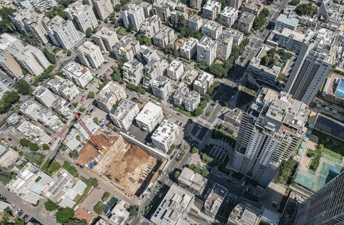 נחלת יצחק בתל אביב במבט מלמעלה: בנייני מגורים עם דודי שמש על הגגות, רחובות, גינות ואתר בנייה.